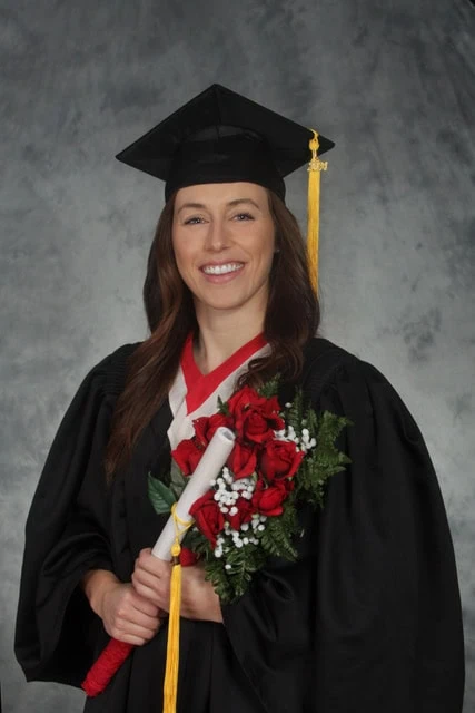 A smiling woman in a graduation outfit